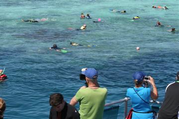 Op het rif snorkelen de toeristen om de vissenpracht onder water te bewonderen.